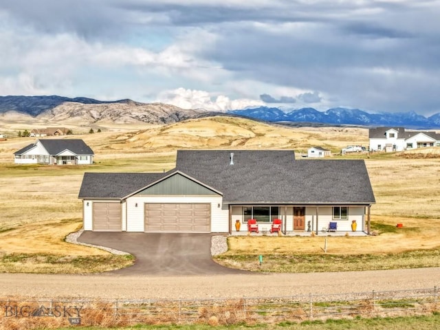 view of front of home with an attached garage, a porch, aphalt driveway, and a mountain view