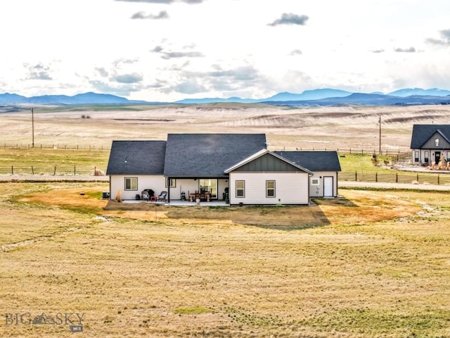 back of property featuring a patio area, a rural view, a mountain view, fence, and a yard