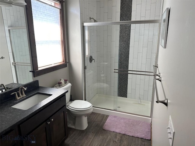full bathroom with vanity, a shower stall, toilet, and wood finished floors