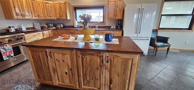 719 Jefferson St, Ennis, MT 59729 - kitchen with freestanding refrigerator, luxury stove, dark countertops, dark tile patterned flooring, and a kitchen island