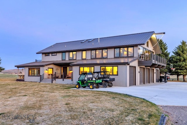 rear view of house featuring metal roof, an attached garage, and concrete driveway