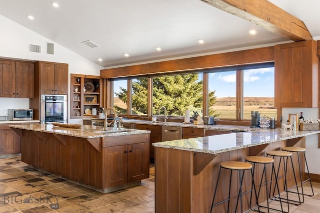 kitchen with stainless steel appliances, visible vents, a sink, and light stone counters
