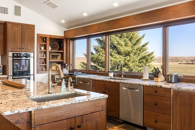 kitchen featuring lofted ceiling, light stone countertops, stainless steel appliances, and a sink
