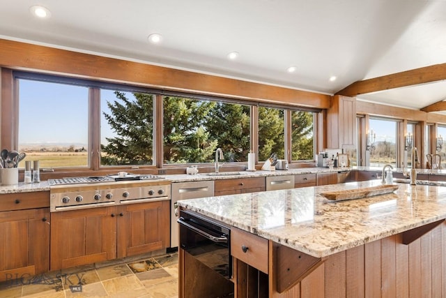 kitchen featuring stainless steel gas cooktop, vaulted ceiling, light stone countertops, and a sink