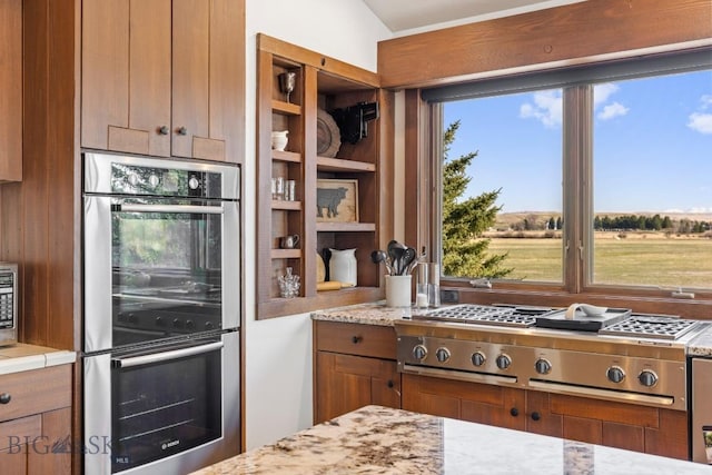 kitchen with brown cabinets, light stone counters, and stainless steel appliances
