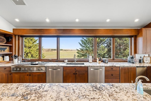 kitchen with stainless steel gas stovetop, visible vents, light stone counters, and a sink