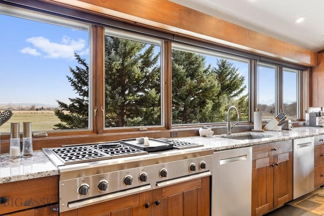 kitchen featuring brown cabinets, a wealth of natural light, appliances with stainless steel finishes, and a sink