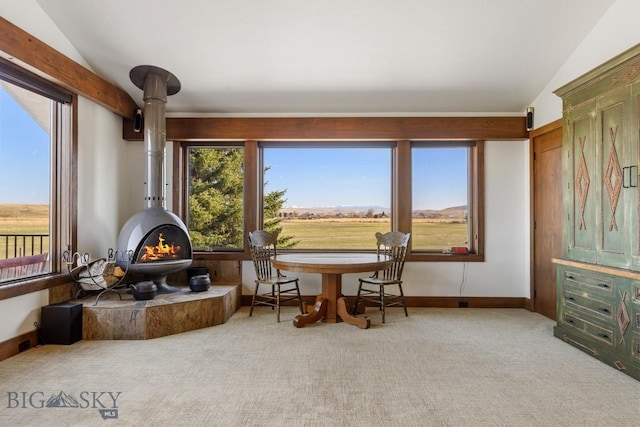 living area with lofted ceiling, a wood stove, and carpet floors