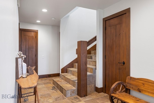 stairs with recessed lighting, stone finish floor, and baseboards