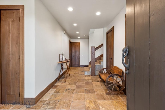 corridor featuring stone finish flooring, baseboards, stairs, and recessed lighting