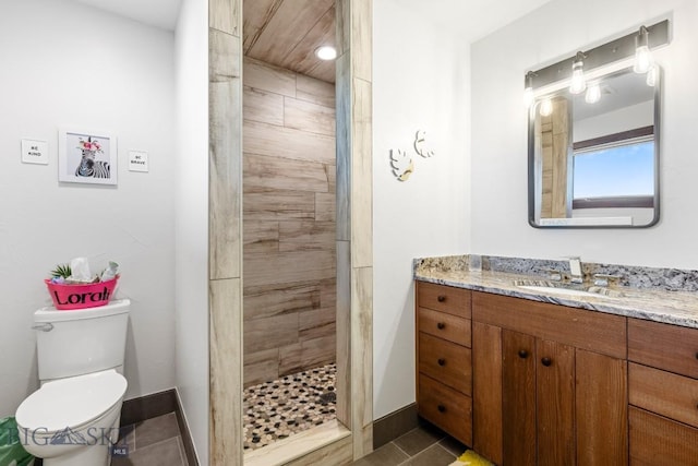 bathroom with baseboards, vanity, a shower stall, and toilet