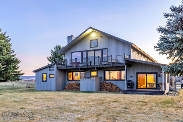 rear view of property featuring a chimney, fence, a deck, and a lawn