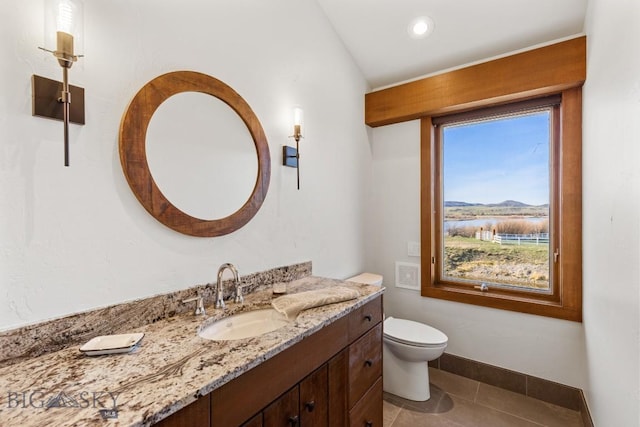 bathroom featuring tile patterned flooring, a water view, toilet, vanity, and baseboards
