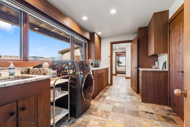 laundry room with stone tile flooring, recessed lighting, a healthy amount of sunlight, and washer / dryer