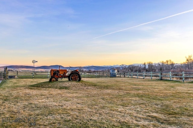 view of yard featuring fence, a rural view, and a mountain view