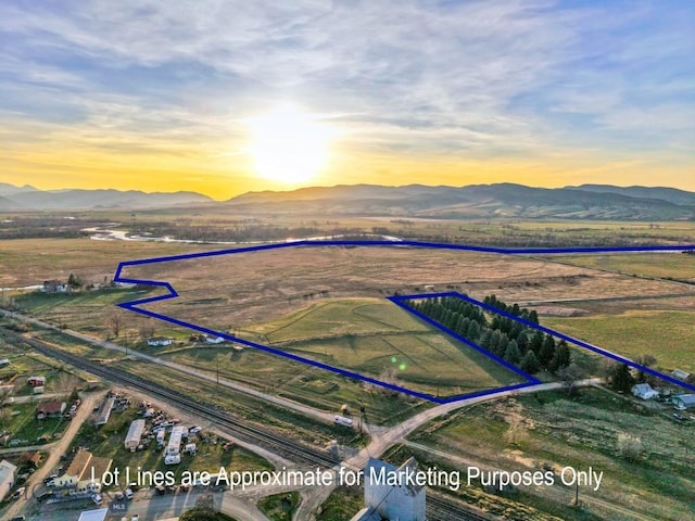 aerial view at dusk featuring a mountain view and a rural view