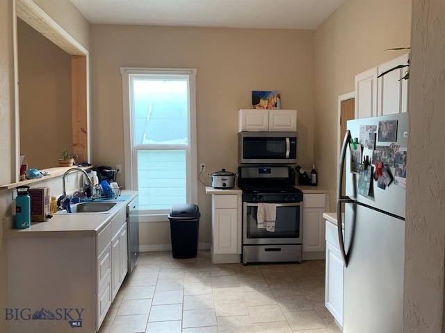 kitchen featuring white cabinets, stainless steel appliances, light countertops, and a sink