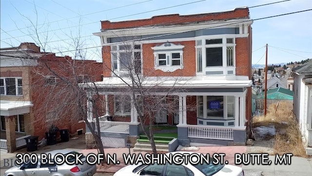 view of property with brick siding and a porch