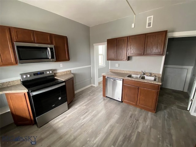 kitchen with stainless steel appliances, light countertops, visible vents, a sink, and light wood-style floors