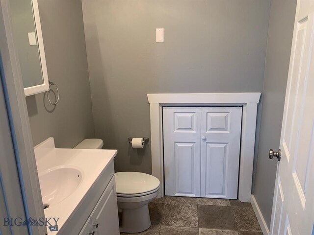 bathroom featuring toilet, vanity, and baseboards