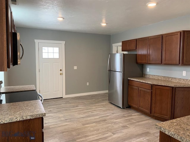 kitchen with baseboards, recessed lighting, stainless steel appliances, and light wood-style flooring
