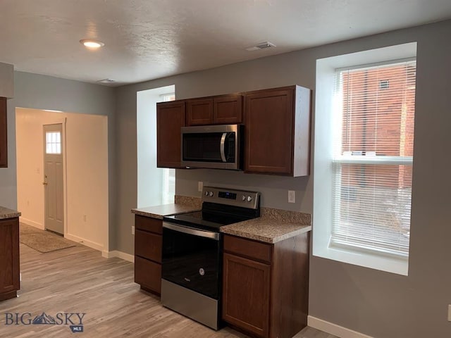 kitchen featuring light countertops, visible vents, light wood-style floors, baseboards, and appliances with stainless steel finishes