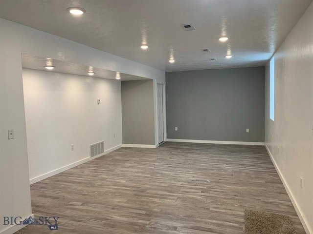 finished below grade area with wood finished floors, visible vents, and baseboards