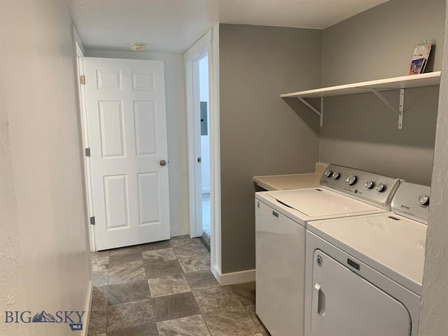 laundry area featuring washing machine and clothes dryer, baseboards, stone finish flooring, and laundry area