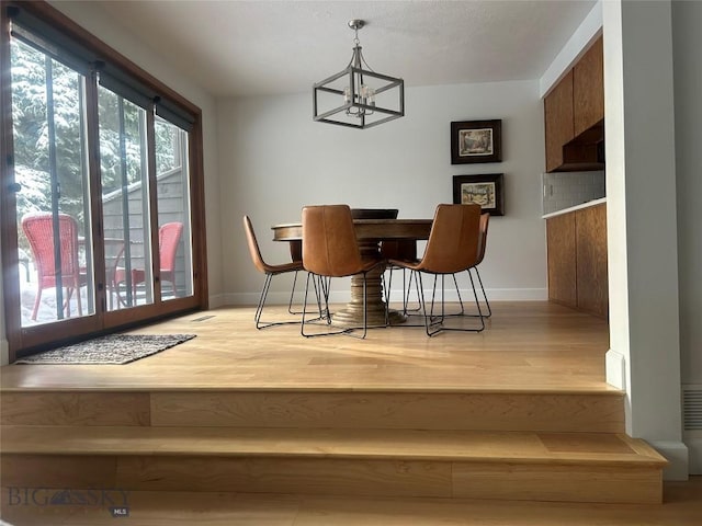 dining space with a chandelier, light wood-style floors, and baseboards