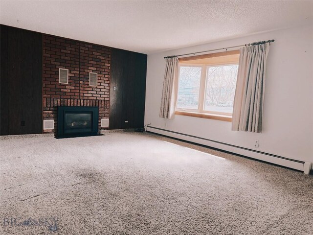 509 1st E, Whitehall, MT 59759 - unfurnished living room with baseboard heating, carpet, a brick fireplace, wooden walls, and a textured ceiling