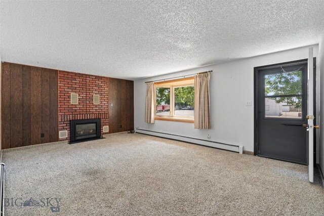 509 1st E, Whitehall, MT 59759 - unfurnished living room featuring baseboard heating, a textured ceiling, wooden walls, carpet, and a brick fireplace