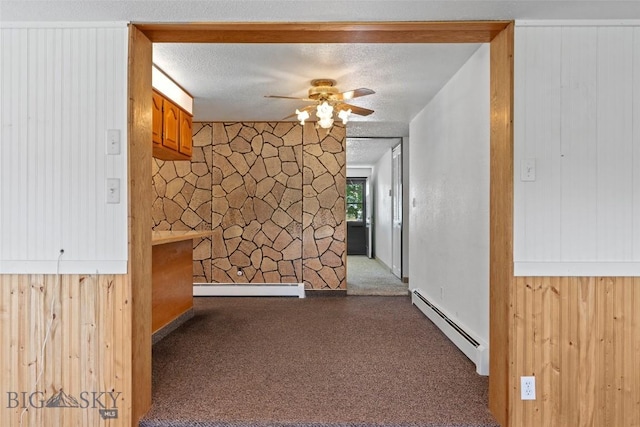 509 1st E, Whitehall, MT 59759 - hallway featuring baseboard heating, dark carpet, wood walls, and a textured ceiling