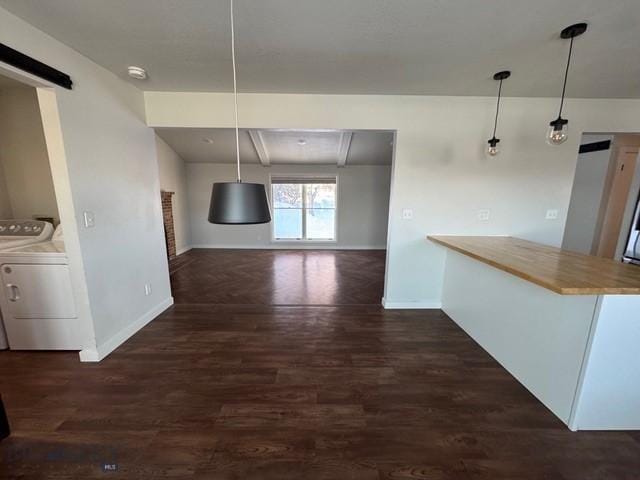 unfurnished dining area with separate washer and dryer, baseboards, and wood finished floors