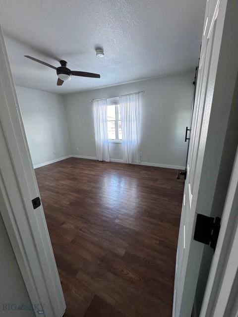 unfurnished room featuring a ceiling fan, baseboards, a textured ceiling, and dark wood finished floors