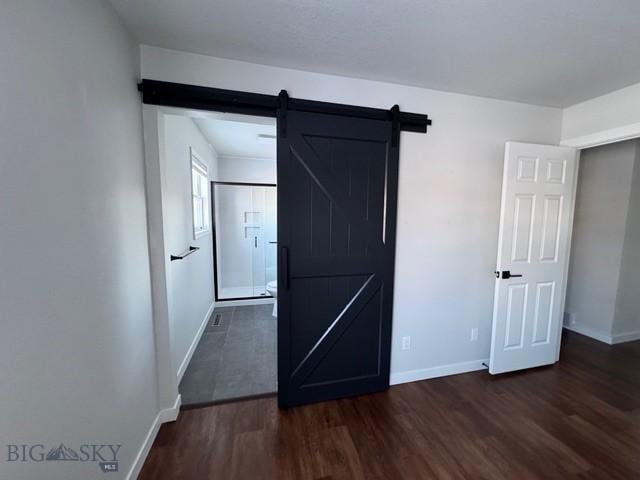 hall with a barn door, baseboards, and dark wood-style flooring