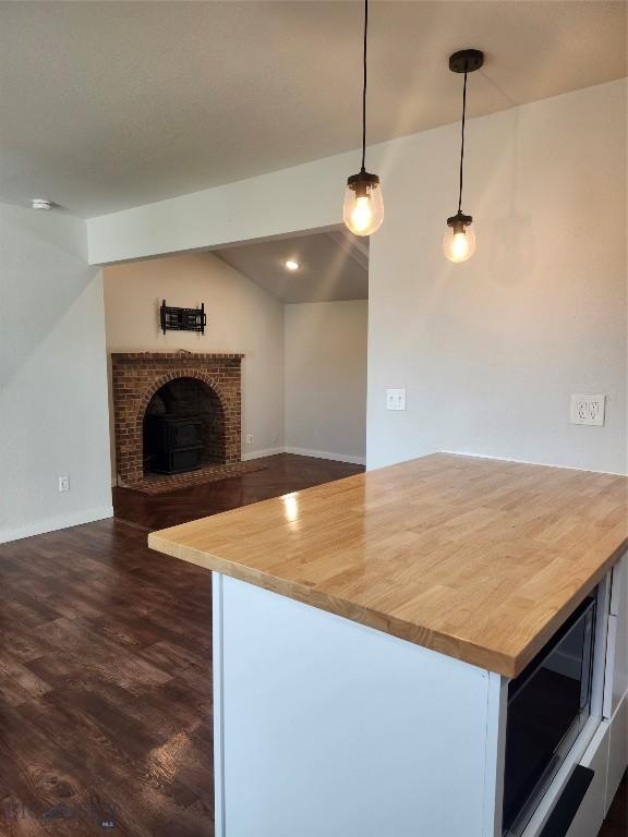 1421 Bluebird Ln, Bozeman, MT 59715 - kitchen with butcher block counters, dark wood-style floors, hanging light fixtures, a fireplace, and open floor plan
