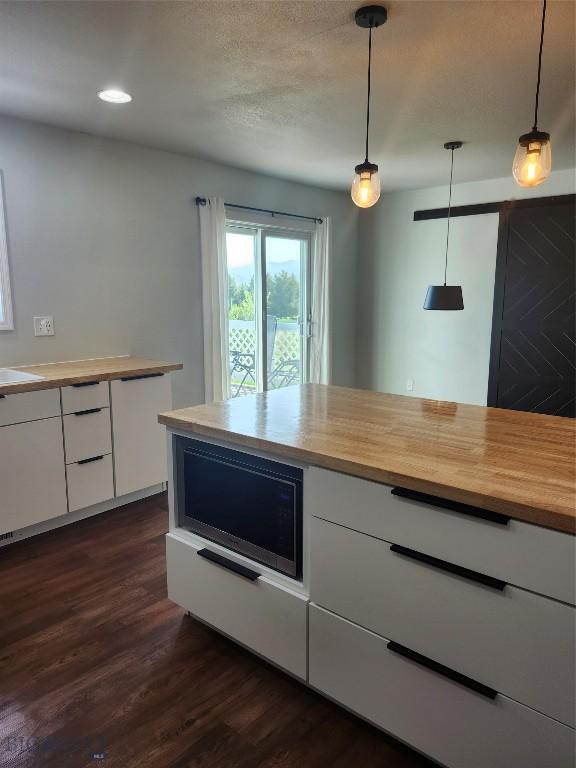 1421 Bluebird Ln, Bozeman, MT 59715 - kitchen featuring wood counters, white cabinets, dark wood-type flooring, hanging light fixtures, and recessed lighting