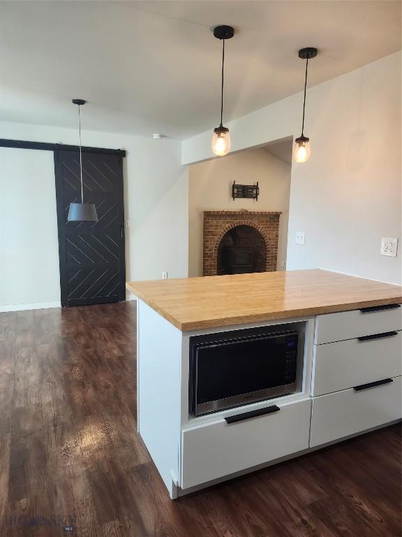 1421 Bluebird Ln, Bozeman, MT 59715 - kitchen with wood counters, dark wood-style flooring, hanging light fixtures, and stainless steel microwave