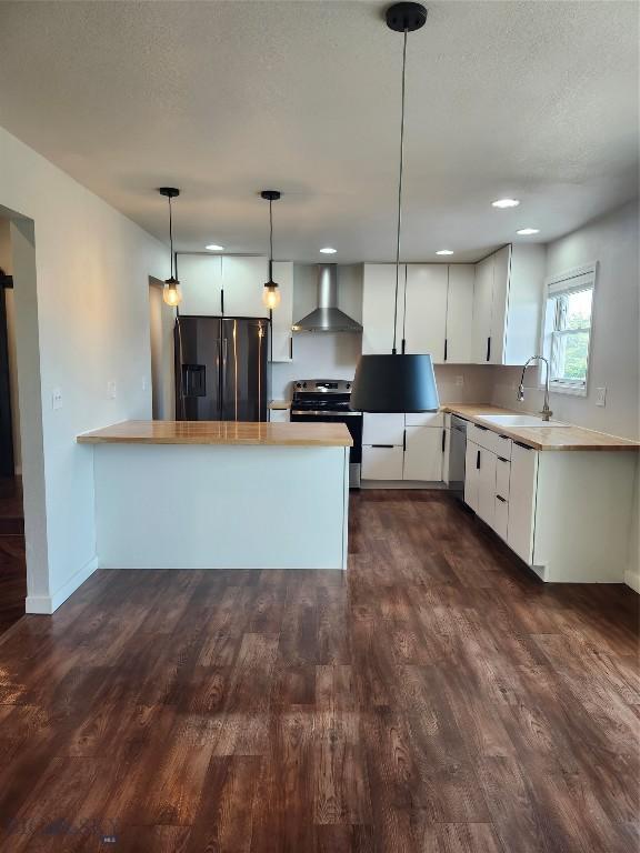 1421 Bluebird Ln, Bozeman, MT 59715 - kitchen featuring stainless steel appliances, wall chimney range hood, a peninsula, white cabinets, and light countertops