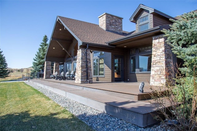 10 Wood Duck Rd, Ennis, MT 59729 - back of property featuring a yard, a wooden deck, a chimney, roof with shingles, and stone siding