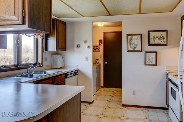 kitchen featuring light floors, light countertops, a sink, white appliances, and baseboards
