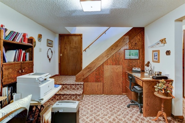 office with wooden walls, carpet floors, and a textured ceiling