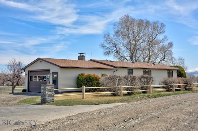 ranch-style home featuring a garage, driveway, a chimney, and fence