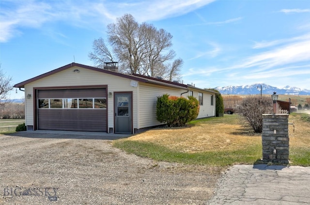 view of side of home with a lawn, a mountain view, driveway, and a garage