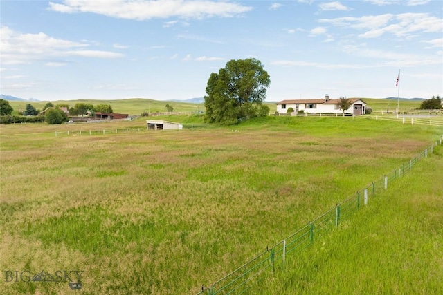 view of yard featuring fence, a rural view, and a mountain view