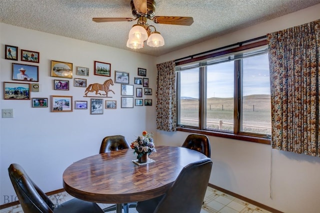 dining room with baseboards, a ceiling fan, and a textured ceiling