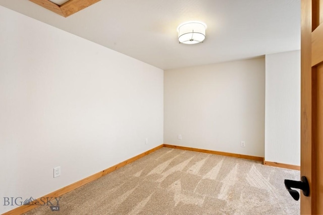 carpeted spare room featuring baseboards