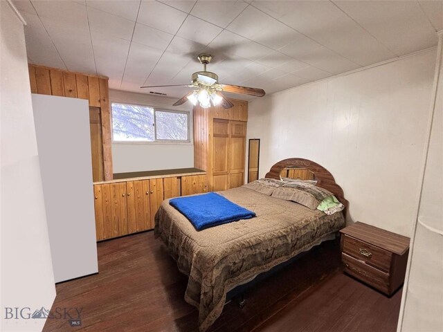 113 N Pacific St, Dillon, MT 59725 - bedroom featuring dark wood-type flooring, wooden walls, and ceiling fan