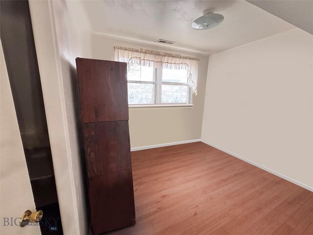 spare room with baseboards, wood finished floors, and visible vents