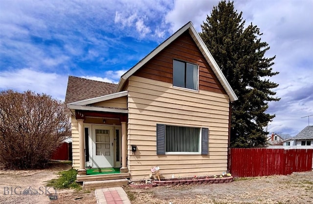 view of front of property featuring fence and a shingled roof